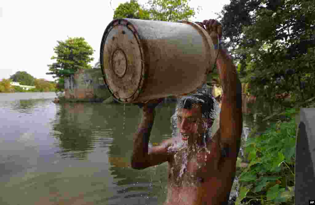 A Sri Lankan bathes with water collected from a leaking pipeline near a polluted canal on International Day for the Eradication of Poverty.