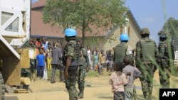 FILE - Peacekeepers of The United Nations Organization Stabilization Mission in the Democratic Republic of the Congo (MONUSCO) stand guard outside the site where a makeshift bomb exploded in Beni, DRC, June 27, 2021.