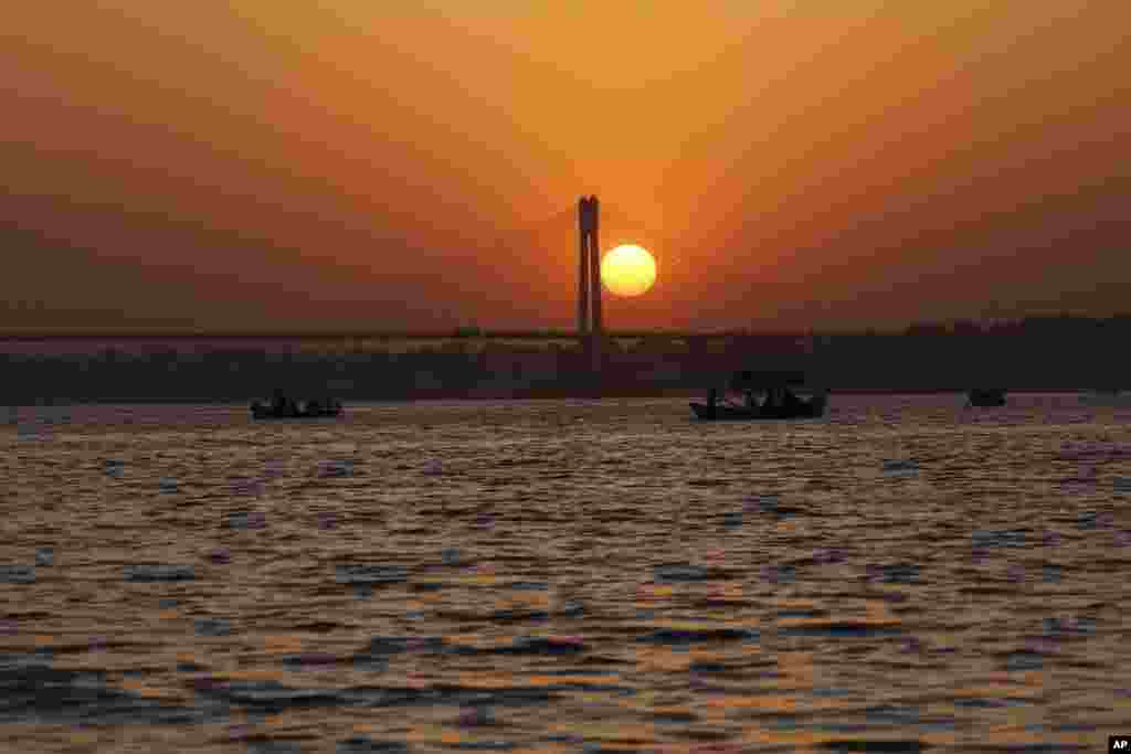 Tourists take a boat ride in the river Ganges during sunset in Allahabad, India.