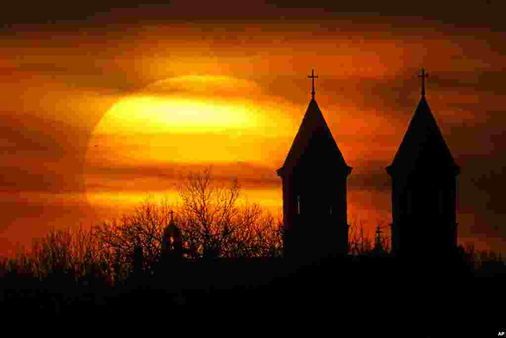 The twin steeples of the Basilica of St. Fidelis is silhouetted against the rising sun in Victoria, Kansas. 