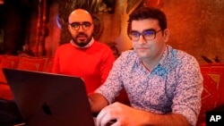 Certfa researchers Nariman Gharib (L) and Amin Sabeti look at a computer at a cafe in London on Dec. 7, 2018. 