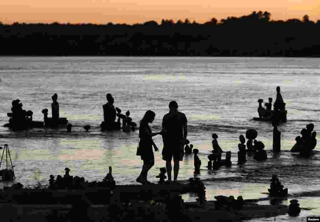 A couple look at stone sculptures at the Remic Rapids in the Ottawa River during sunset at Ottawa, Canada, July 23, 2014.