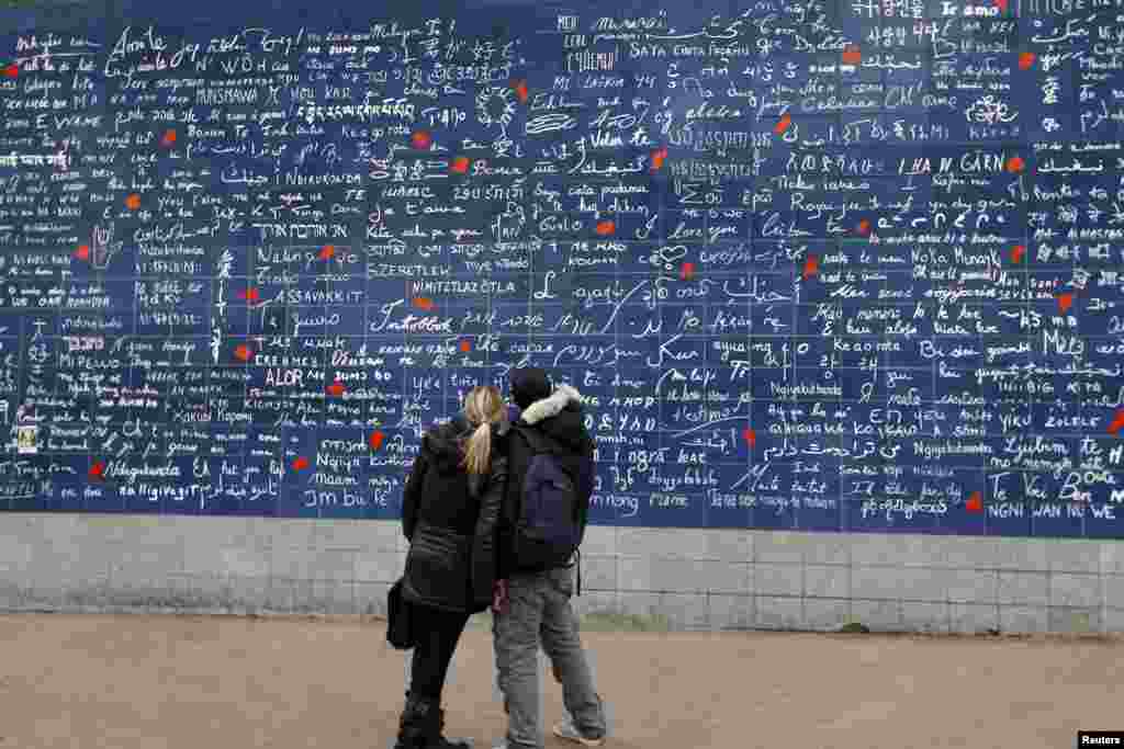 A couple stands in front the &#39;I love You : The Wall&#39; art work by Frederic Baron and Claire Kito on Saint Valentine&#39;s Day in Paris, France. 