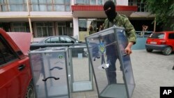 Пророссийский сепаратист уносит урну с избирательного участка в Донецке