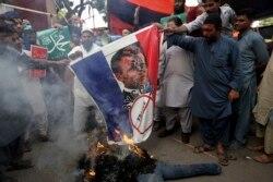 Supporters of Jamaat-e-Islami, a religious political party, burns a representation of a French flag with a defaced image of French President Emmanuel Macron during a protest.