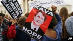 Protesters in front of the Supreme Court hold signs with an image of Judge Brett Kavanaugh that reads "Kava Nope" and "We Believe Christine Blasey Ford" in Washington, Sept. 24, 2018. 