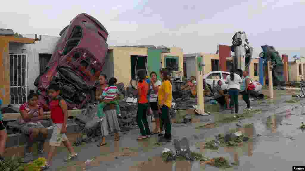 Moradores à porta das suas casas e ao lado dos carros danificados após um tornado ter atingido a cidade de Ciudad Acuna, Estado de Coahuila, México. 25 de Maio