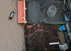 In a photo taken with a drone, a man is seen using an inflatable mattress during flooding caused by the overflowing Cachoeira river, in Itabuna, Bahia state, Brazil, Dec. 26, 2021.