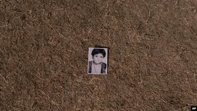 A photo of Najieh dressed as a boy at a young age lies in a grass, in Kabul, Afghanistan, Sunday, Dec. 19, 2021.