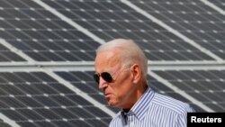 FILE - Joe Biden, then U.S. vice president, walks past solar panels while touring the Plymouth Area Renewable Energy Initiative in Plymouth, New Hampshire, June 4, 2019.