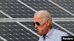 FILE - Joe Biden, then U.S. vice president, walks past solar panels while touring the Plymouth Area Renewable Energy Initiative in Plymouth, New Hampshire, June 4, 2019. As president, Biden will use executive action on Monday to help bridge a solar panel supply gap.