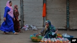 Two Bangladeshi Muslim women walk past a Hindu woman selling flowers by a roadside in Dhaka, Bangladesh, March 28, 2016. Hindus, along with Buddhists, represent the main minority groups in the majority Muslim country.