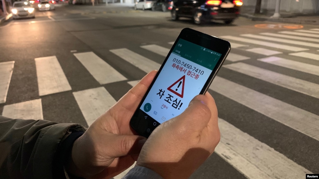 A researcher demonstrates an application that gives an alert to a user distracted by using smart phone while crossing a zebra crossing, in Ilsan, South Korea, March 12, 2019.