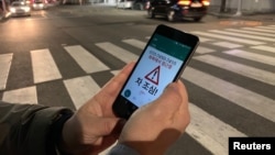A researcher demonstrates an application that gives an alert to a user distracted by using smart phone while crossing a zebra crossing, in Ilsan, South Korea, March 12, 2019.