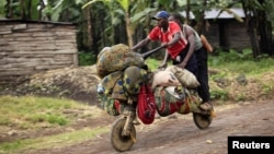 People ride with their belongings on a wooden bicycle as they flee from renewed fighting between Congolese army and M23 rebels near the eastern Congolese city of Goma, July 24, 2012. 