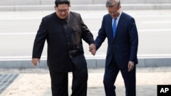 FILE - North Korean leader Kim Jong Un (L) and South Korean President Moon Jae-in cross the border line at the border village of Panmunjom in Demilitarized Zone, April 27, 2018. 
