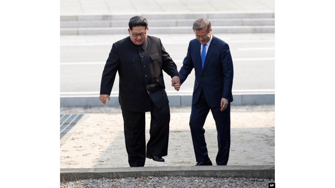 FILE - North Korean leader Kim Jong Un (L) and South Korean President Moon Jae-in cross the border line at the border village of Panmunjom in Demilitarized Zone, April 27, 2018.