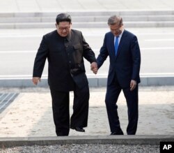 FILE - North Korean leader Kim Jong Un (L) and South Korean President Moon Jae-in cross the border line at the border village of Panmunjom in Demilitarized Zone, April 27, 2018.