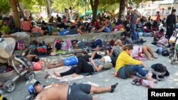 Integrantes de una caravana de migrantes que avanza por México descansan en un parqie de Chahuites el 8 de noviembre de 2021.