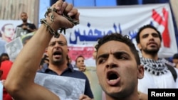 Journalists and members of the April 6 movement protest against the restriction of press freedom and demand the release of detained journalists in front of the Press Syndicate in Cairo, June 10, 2015. 
