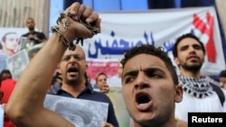 Journalists and members of the April 6 movement protest against the restriction of press freedom and demand the release of detained journalists in front of the Press Syndicate in Cairo, June 10, 2015. 