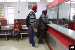 Indians stand to deposit discontinued currency notes at a post office on the outskirts of Jammu, India, Dec. 29, 2016.