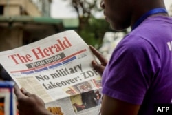 A man reads the front page of a special edition of The Herald newspaper about the crisis in Zimbabwe with the headline 'No military takeover - ZDF' on Nov. 15, 2017 in Harare.