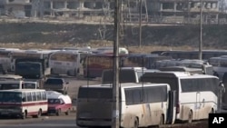 In this still image taken from video from Syria TV vehicles wait to cross into east Aleppo at Ramouseh crossing point, Sunday, Dec. 18, 2016. Dozens of vehicles were on standby at the Ramouseh crossing point near Aleppo on Sunday morning.