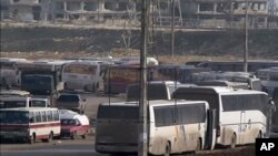 In this still image taken from video from Syria TV vehicles wait to cross into east Aleppo at Ramouseh crossing point, Dec. 18, 2016. Dozens of vehicles were on standby at the Ramouseh crossing point near Aleppo on Sunday morning.