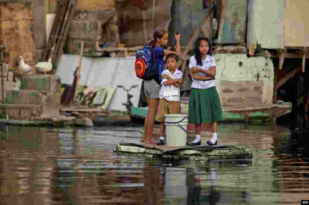필리핀 마닐라 북부 말라본에서 초등학생들이 개학 첫 날 임시뗏목을 타고 등교하고 있다.&nbsp;