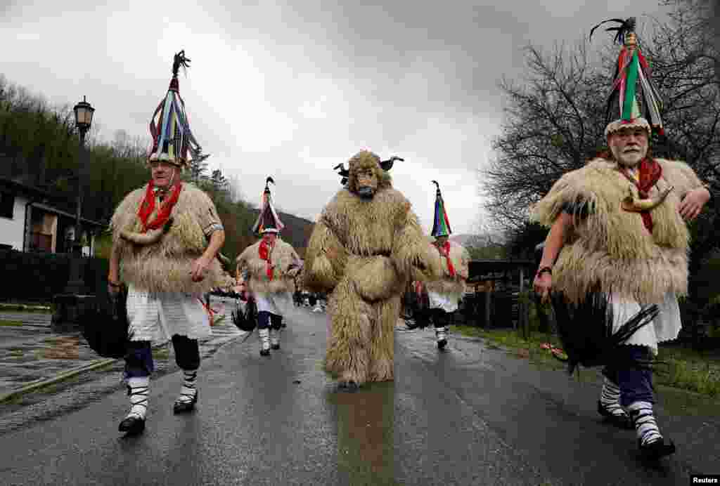 A man dressed as a bear accompanies bell-wearing dancers known as Joaldunak, performing a traditional dance to keep evil spirits away and awaken the coming spring, during carnival celebrations in Ituren, northern Spain.