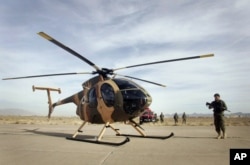 FILE - An Afghan soldier stands guard near a helicopter donated by the U.S. in Shindand district of Herat province, west of Kabul, Afghanistan, Dec. 10, 2011.