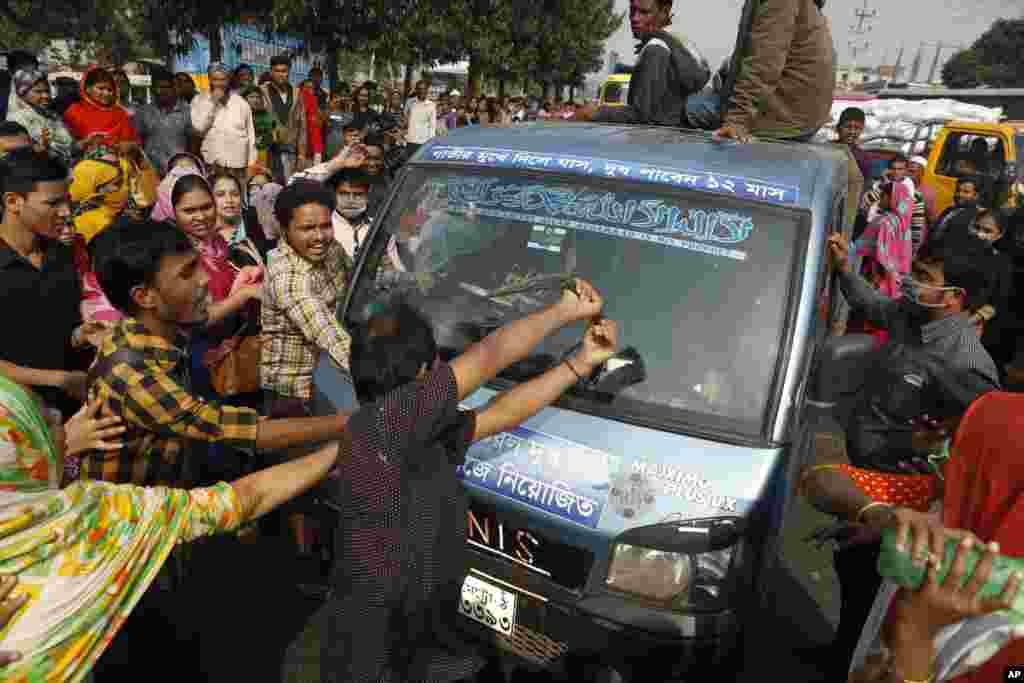 Bangladeshi clothing workers damage a vehicle during a protest in Savar, on the outskirts of Dhaka. Thousands of garment workers have staged demonstrations to demand better wages, shutting down factories in and near the capital city.