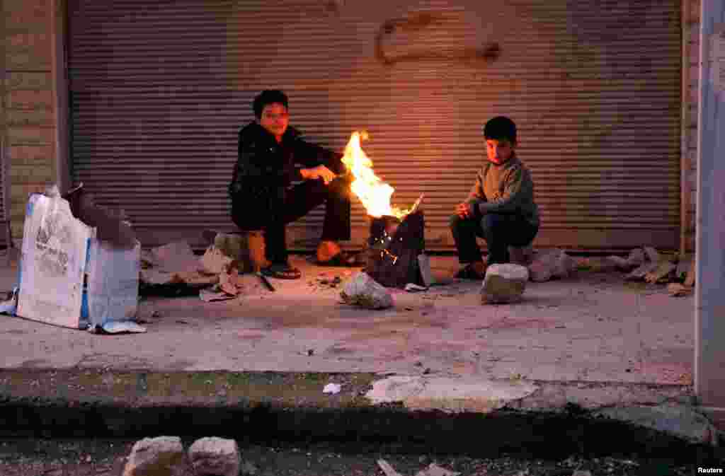 Boys warm up next to a fire outside a building in the Ain Tarma neighborhood of Damascus, February 5, 2013. 