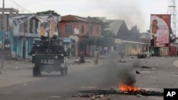 20일 콩고민주공화국 킨샤샤사에서 경찰이 시위대가 지나간 자리에 놓인 화염 옆을 지나고 있다.