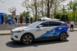 Robotaxi Baidu Apollo melewati penyiapan konter layanan pelanggannya di Taman Shougang di Beijing, Minggu, 2 Mei 2021. (AP)