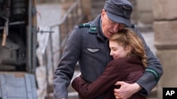 Geoffrey Rush, kiri, dan Sophie Nélisse dalam sebuah adegan di film "The Book Thief," tenting seorang anak perempuan yang suka buku.