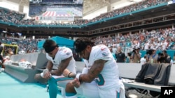 Miami Dolphins wide receiver Kenny Stills (10) and Miami Dolphins wide receiver Albert Wilson (15) kneel during the national anthem before an NFL football game against the Tennessee Titans, Sunday, Sept. 9, 2018, in Miami Gardens, Florida.
