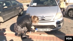 Žena lepi nalepnice preko svoje tablice na prelazu Merdare (Foto: VOA)