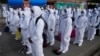 FILE - Health care workers, dressed in full protective gear, take part in a ceremony kicking off a door-to-door COVID-19 vaccination campaign, in El Alto, Bolivia, Sept. 16, 2021.
