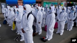 FILE - Health care workers, dressed in full protective gear, take part in a ceremony kicking off a door-to-door COVID-19 vaccination campaign, in El Alto, Bolivia, Sept. 16, 2021.