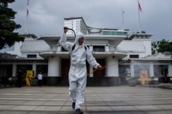 Seorang petugas mengenakan alat pelindung diri (APD) menyemprotkan disinfektan di depan Kantor Walikota yang ditutup akibat pandemi COVID-19 yang terus berlanjut di Bandung, provinsi Jawa Barat, 28 Juni 2021. (REUTERS)