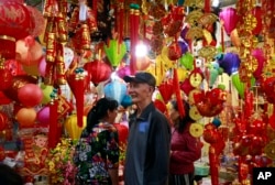 In this Sunday, Feb. 3, 2019, photo, people shop for decorative ornaments in Hanoi, Vietnam. Vietnam is celebrating the Lunar New Year of the Pig, the biggest annual festival of the year. (AP Photo/Hau Dinh)