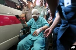 Indonesian Corruption Eradication Commission (KPK) investigator Novel Baswedan, center, who was injured in an attacked by unidentified assailants sits on a wheelchair as he leaves the general hospital where he was treated.