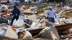 Para warga berusaha mencari sisa barang milik mereka dintara puing-puing rumah yang hancur akibat diterjang tornado di Bowling Green, Kentucky, pada 11 Desember 2021. (Foto: AP/Michael Clubb)