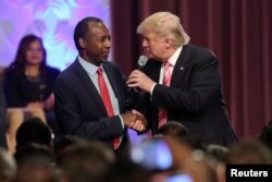 FILE - Donald Trump shakes hands with Ben Carson as he attends a church service in Detroit, Michigan, Sept. 3, 2016.