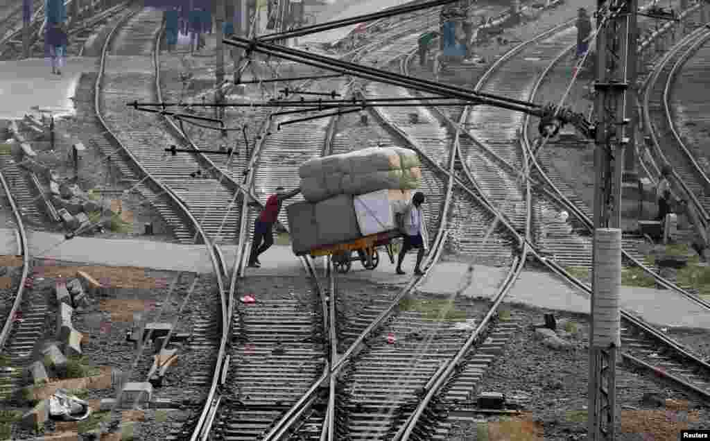 Men transport goods across railway tracks in New Delhi, India.