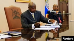 FILE - Uganda President Yoweri Museveni signs an anti-homosexual bill into law at the state house in Entebbe, 36 km (22 miles) south west of capital Kampala, Feb. 24, 2014. 