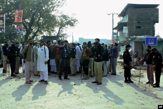 Police officers control an angry crowd protesting against a mentally unstable man accused of blasphemy, in Mandani, an area of Charsadda district, Pakistan, Nov. 29, 2021.