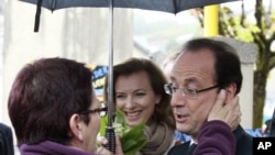 Socialist Party candidate for the presidential election Francois Hollande meets a resident with his companion Valerie Trierweiler, center, as he tours Tulle, after voting , May 6, 2012. 
